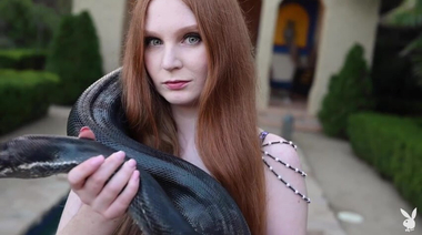 Рыжая ведьма эротично позирует с черным питоном